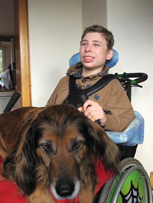 Fotografie eines Jungen im Rollstuhl mit einem Hund