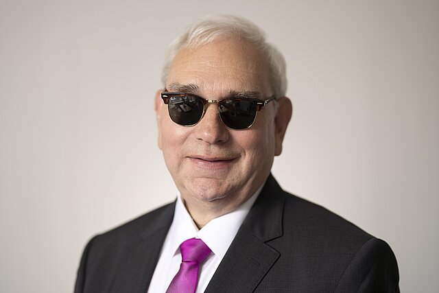 Fotografie des DBSV-Präsident Hans-Werner Lange  im Anzug und mit dunkler Brille.